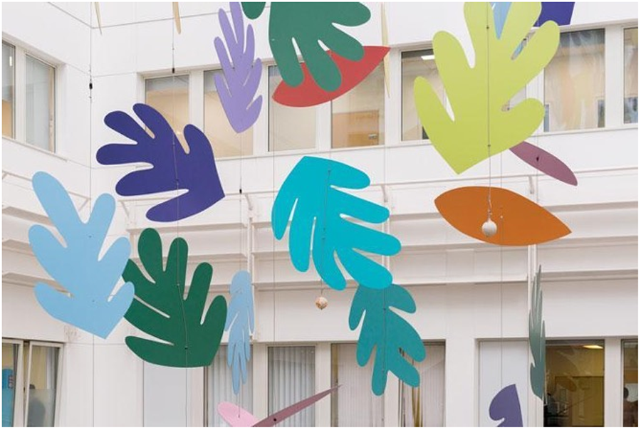 Brightly coloured leaf shapes in Sian Tucker’s suspended mobile hang across the hospital atrium.
