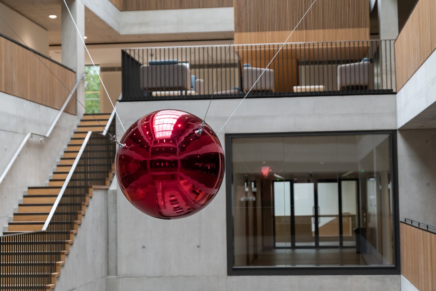 A reflective red sphere suspended by cables in the Zayed Centre for Research atrium.