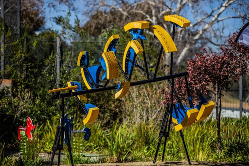 Yellow and blue circular cut-out elements of Shift-19 stand on a steel frame in a hospital garden.