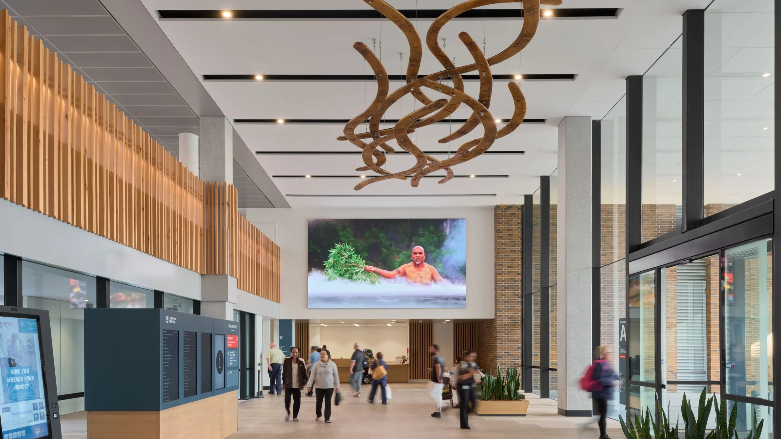 Carved timber forms hang above the foyer of Liverpool Hospital, with the companion Burbangana digital artwork on the far wall.